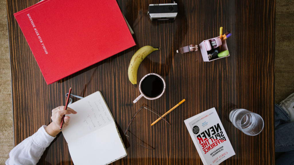 Overhead view of a work table with a notebook, pencils, coffee, books, and business tools for a Xero setup for tradies.